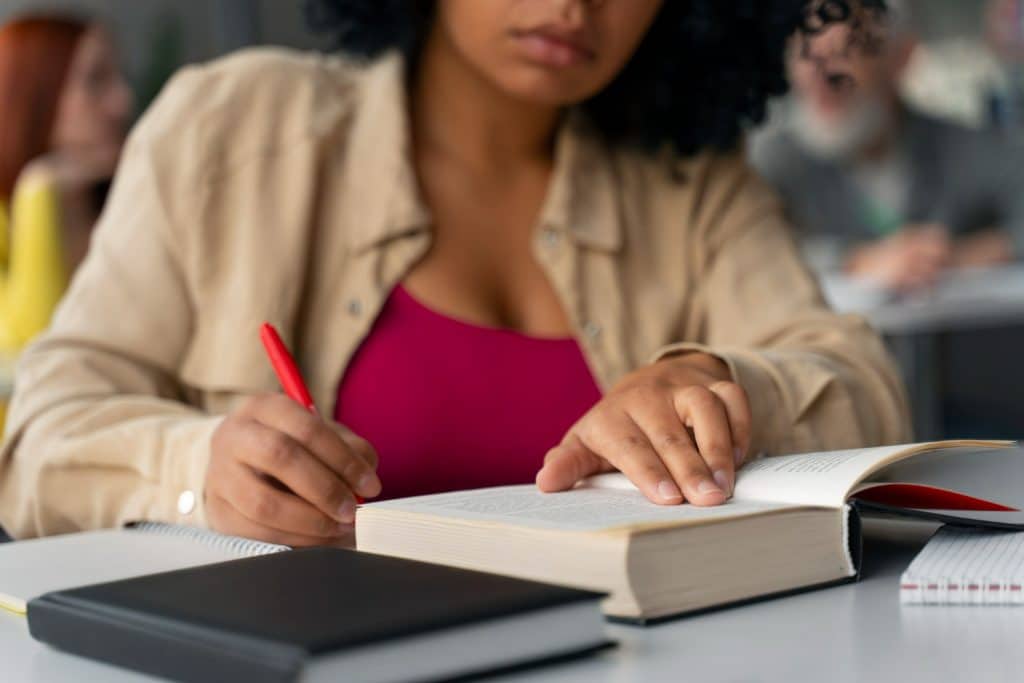 Estudante focada lendo livro em sala de aula.