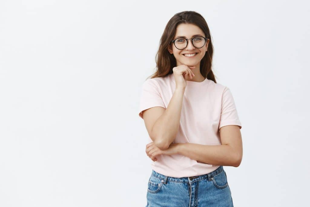 Mulher sorrindo com óculos e camiseta rosa, destacando a inteligência além do QI.