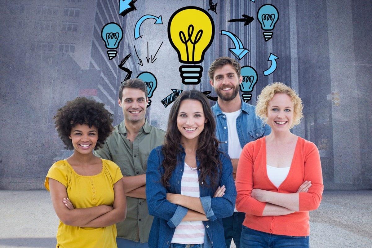 Grupo de pessoas sorrindo com símbolos de lâmpadas e setas ao fundo, representando ideias e criatividade.