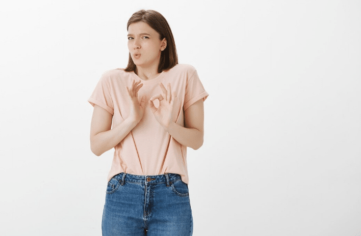 Mulher com expressão desconfortável e gesto defensivo com as mãos