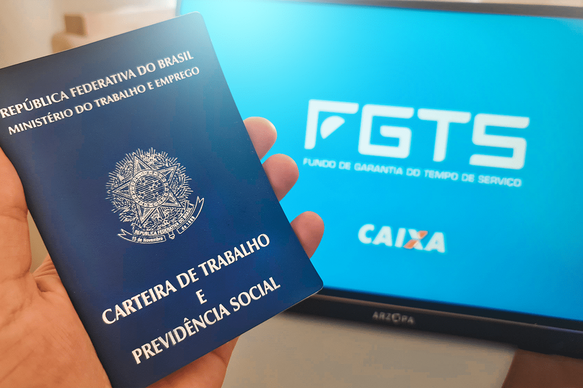 Carteira de Trabalho e tela do FGTS no computador, representando a consulta ao saque-aniversário FGTS