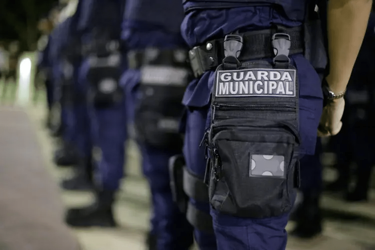 Guarda municipal com rádio comunicador em mãos, simbolizando a comunicação durante o serviço.