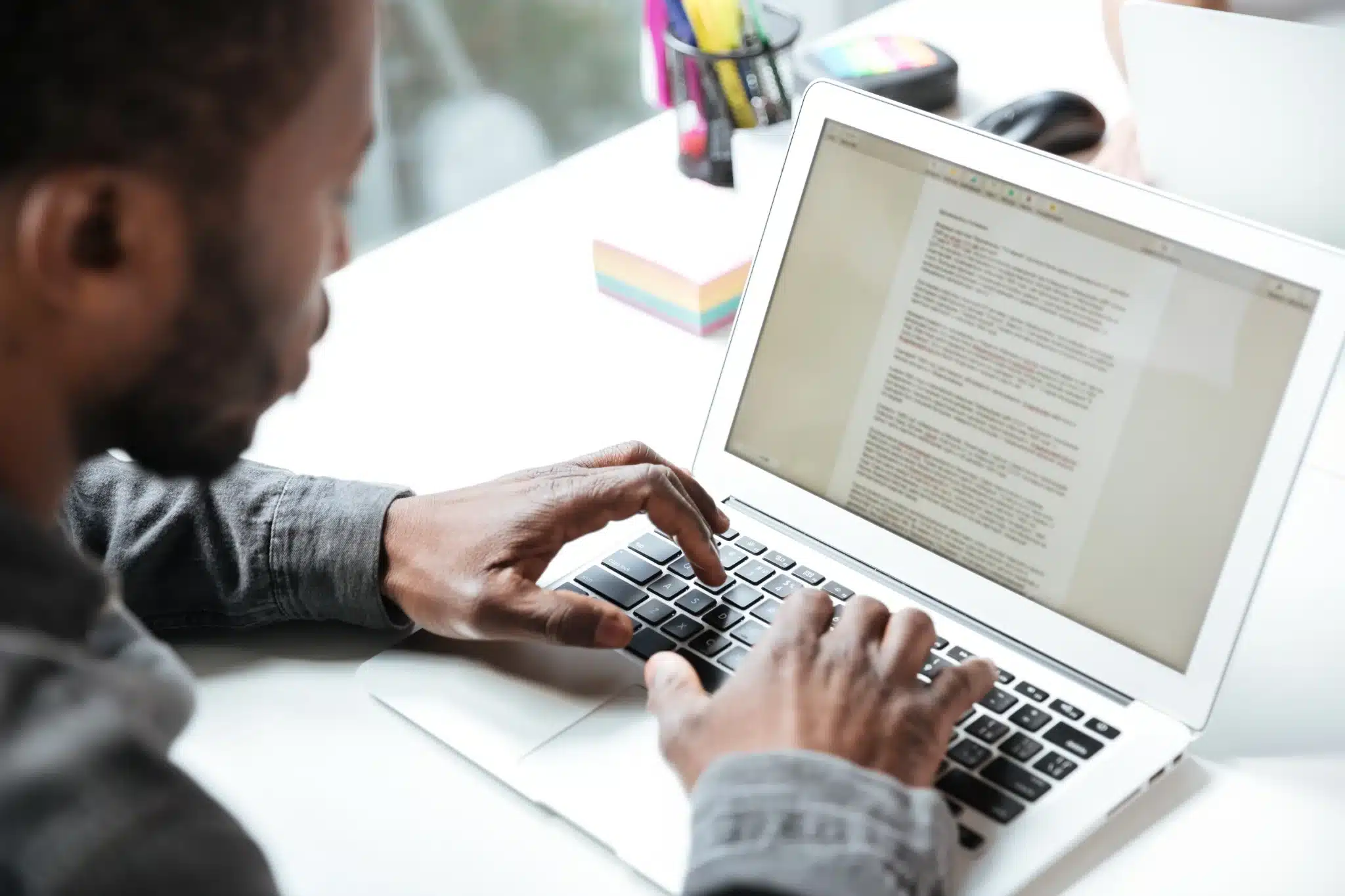 Homem digitando no notebook com documento aberto, representando atenção ao prazo de inscrições em concurso público.