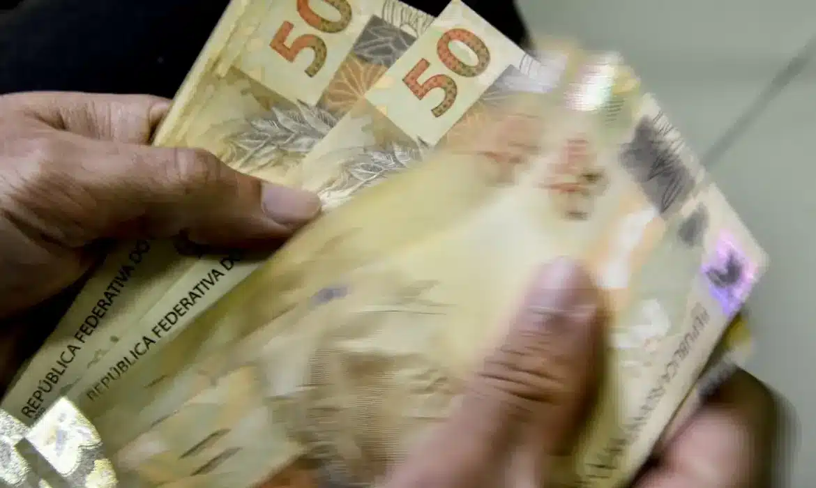 Pessoa contando notas de cinquenta reais.