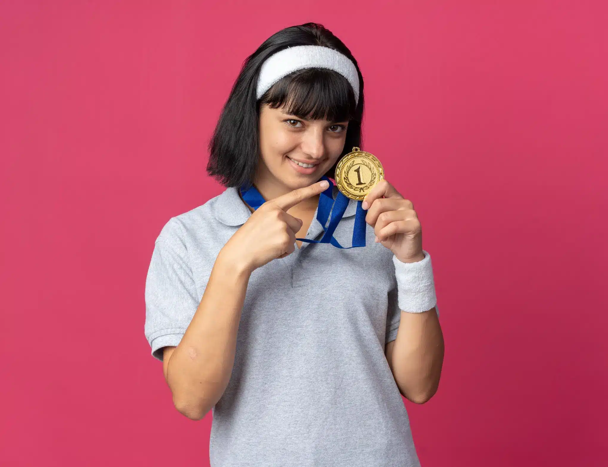 Jovem com medalha de ouro sorrindo e apontando para a medalha, simbolizando a competição nacional de educação financeira para ganhar R$ 400.