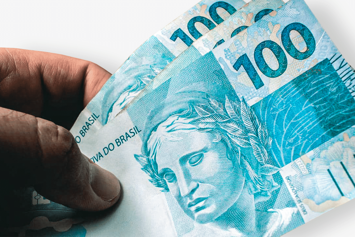 Pessoa segurando nota de 100 reais do Brasil.