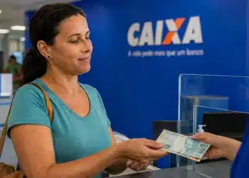 Mulher recebendo cédulas em uma agência da Caixa, representando o saque de até R$ 6.220 do FGTS a partir de 21 de julho.