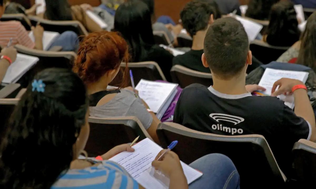 Jovens em auditório anotando e estudando, se preparando para as provas do Enem.