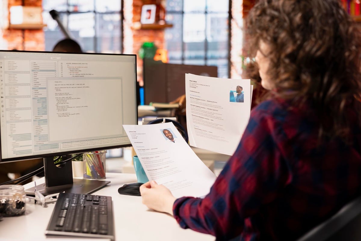 Pessoa avaliando currículos em frente ao computador