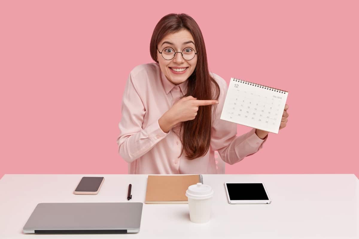 Mulher entusiasmada apontando para calendário de dezembro destacando prazo do décimo terceiro
