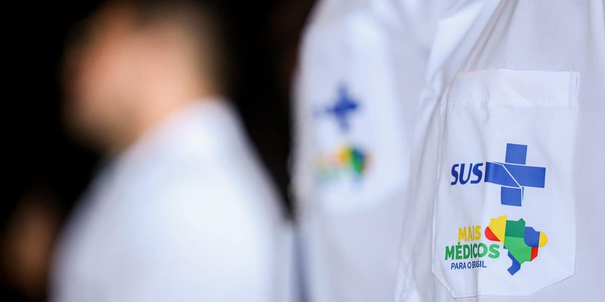 A quem se destina o pagamento Detalhe de jaleco médico branco com logotipos do SUS e Programa Mais Médicos para o Brasil