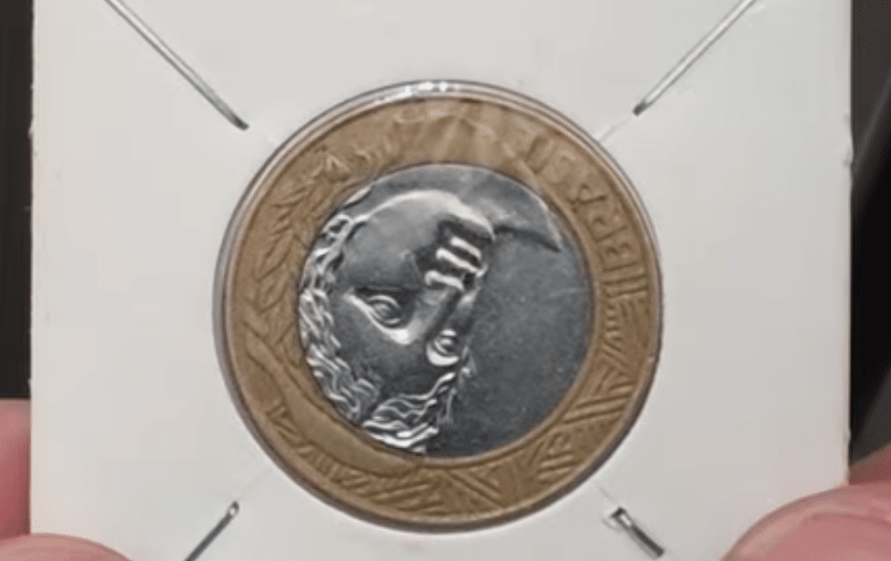 Detalhe da efígie da República em uma moeda de 1 real com o reverso invertido, pronta para avaliação.