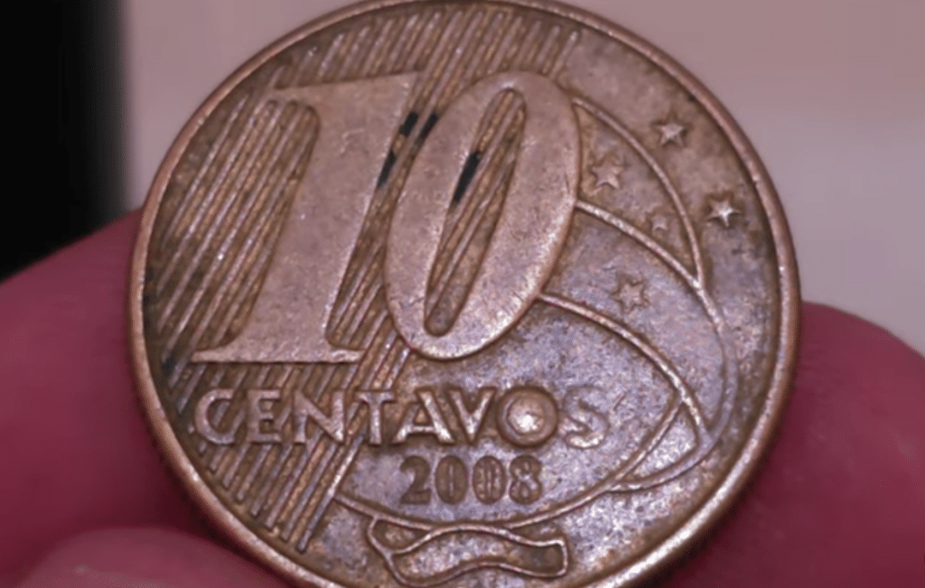 Close-up da moeda de 10 centavos de 2008, destacando o erro de cunhagem "O entupido" na palavra "CENTAVOS".