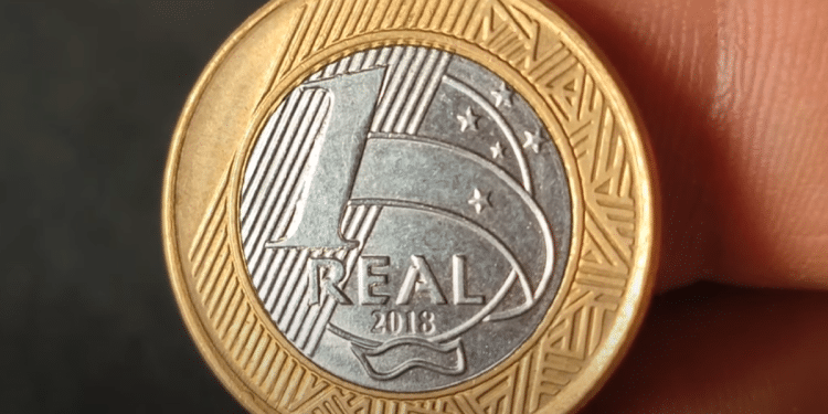 Moeda de 1 real de 2018 sendo segurada, mostrando o anverso com o valor e o ano.