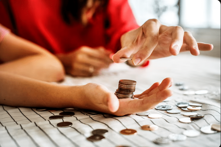 Mãos segurando moedas antigas e de real, simbolizando uma possível fonte de renda extra com a venda de moedas raras.