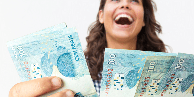 Mulher celebrando com notas de cem reais representando benefício liberado pela Caixa