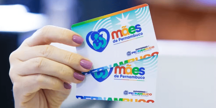 Mãos segurando cartão do programa Mães de Pernambuco mostrando logotipo colorido do benefício social