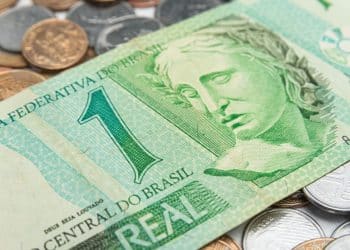 Close-up da cédula brasileira de 1 Real de cor verde, com a efígie da República, sobreposta a moedas, ilustrando uma nota procurada por colecionadores (numismatas).