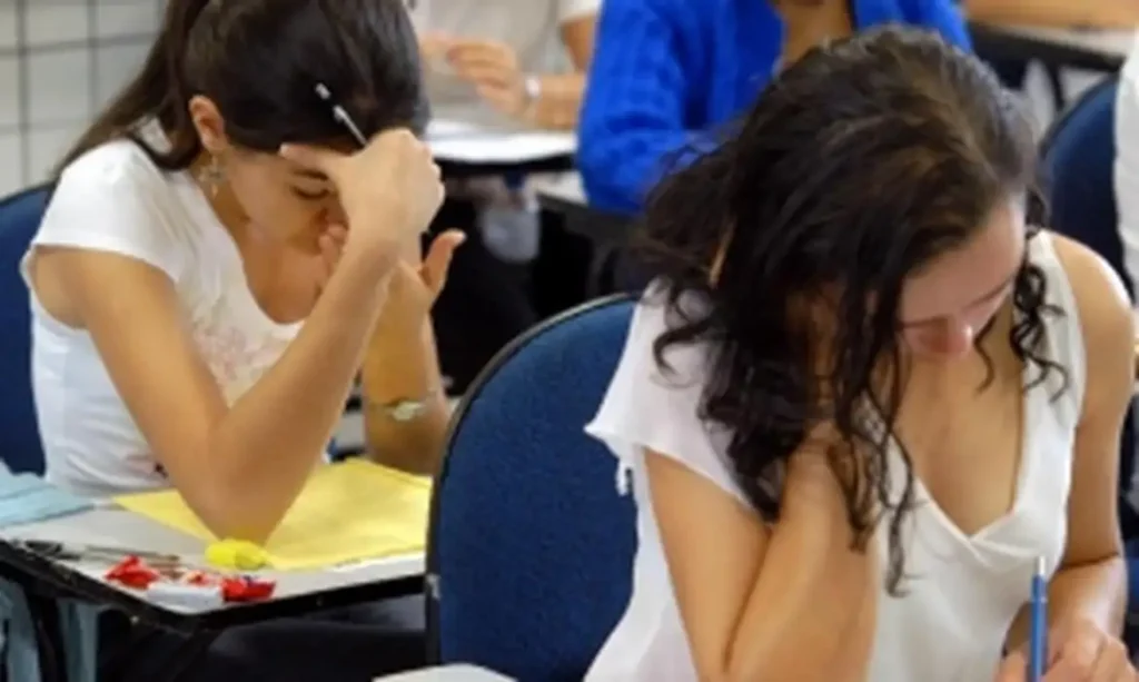 Duas estudantes em um momento de concentração na prova, focadas em escrever a redação do Enem.