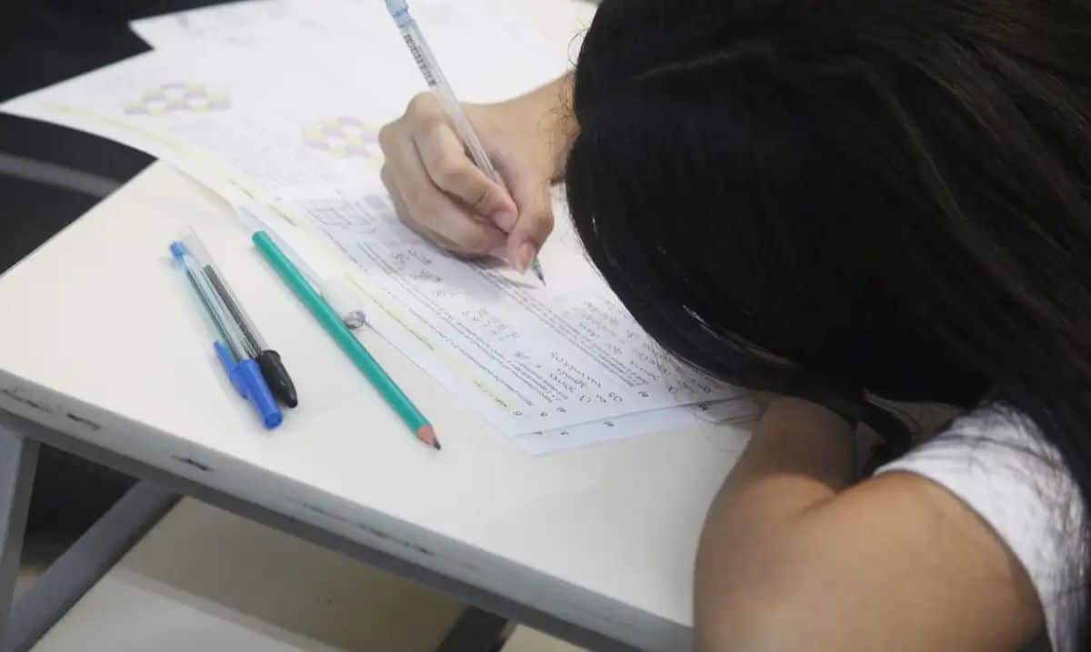 Estudante escrevendo uma redação do Enem 2025 em uma prova, simbolizando o momento de concentração para desenvolver um bom texto.