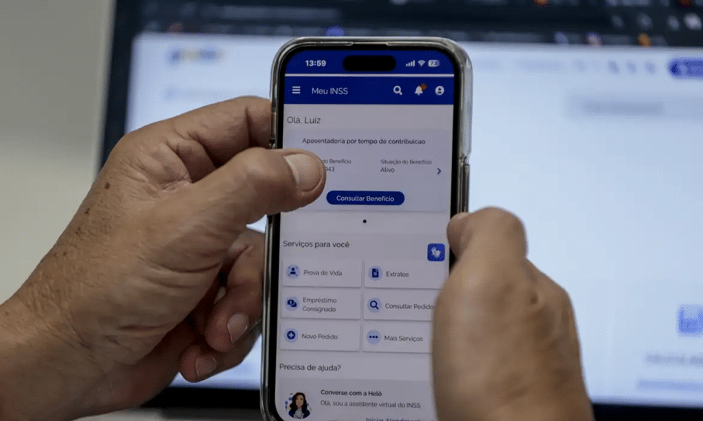 Pessoa segurando celular com aplicativo Meu INSS aberto na tela de consulta de benefício.