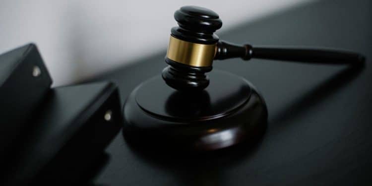 Um martelo de juiz de madeira com detalhes dourados, repousando sobre uma base redonda escura em uma mesa, simbolizando justiça, lei e autoridade.