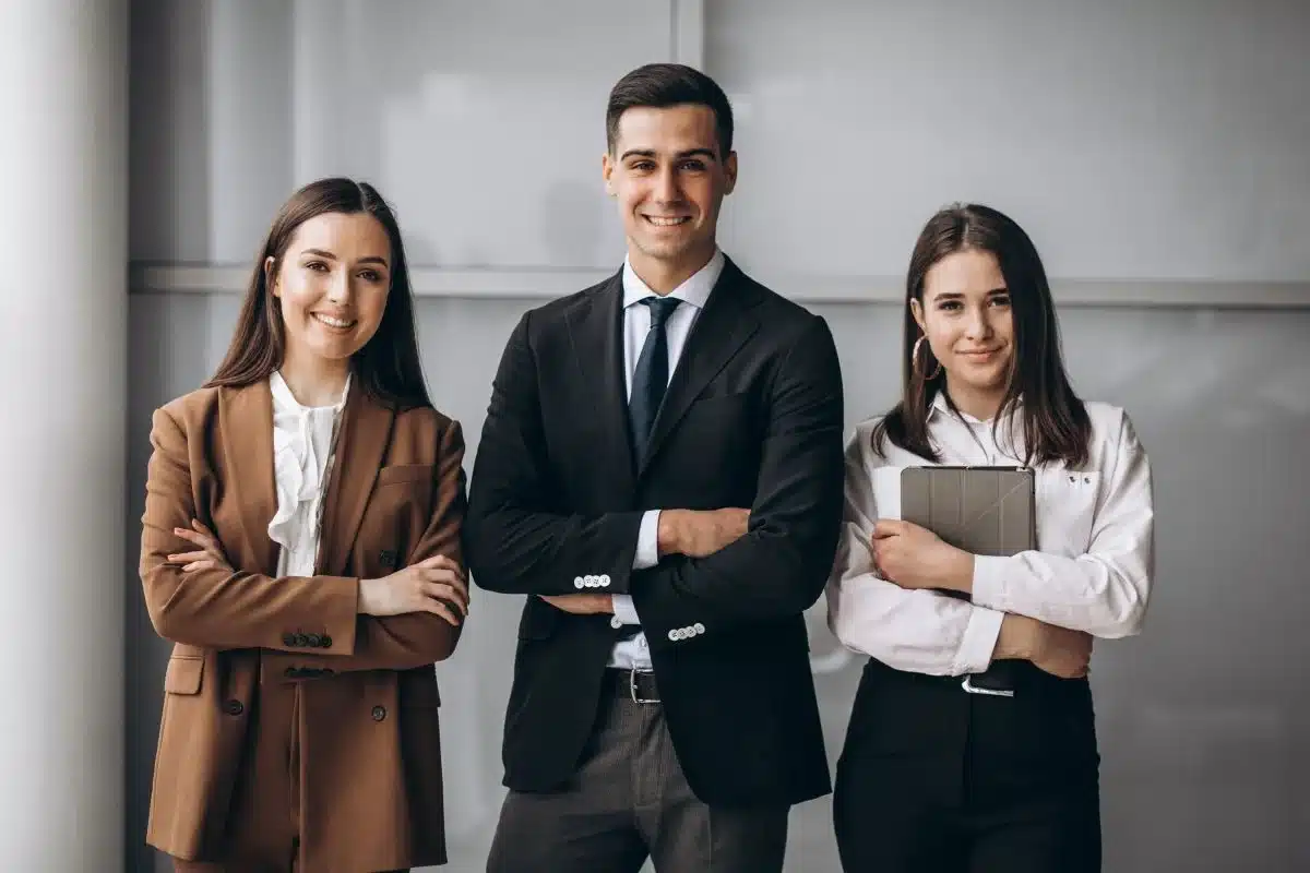 Três profissionais sorrindo em um ambiente de escritório, destacando áreas com alta remuneração como diretoria, tecnologia e jurídico.