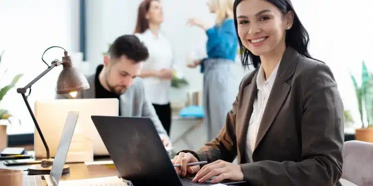 Mulher trabalhando em um escritório moderno em frente ao computador, com foco em profissões sem exigência de diploma.
