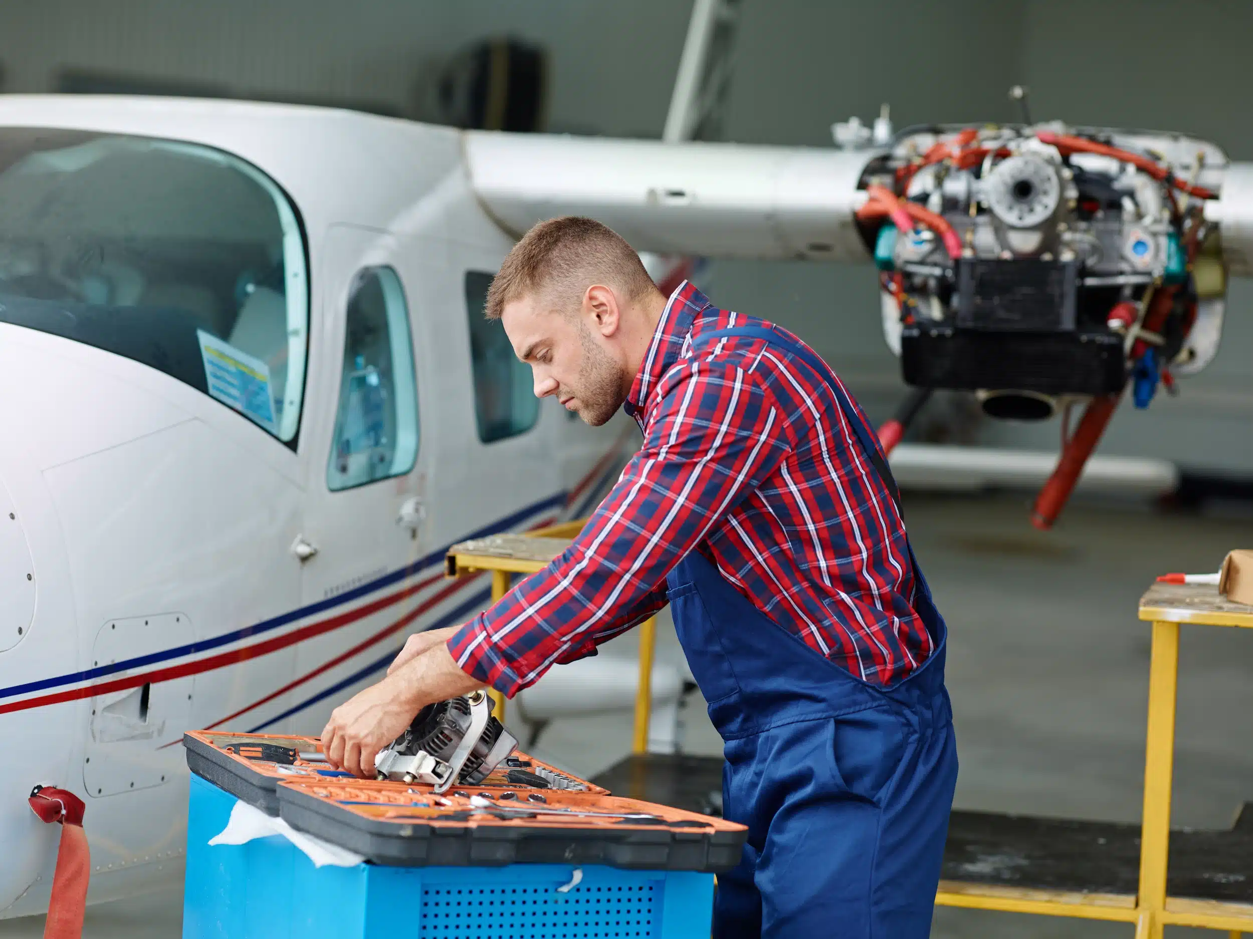 Técnico realizando manutenção em aeronave, com foco em reparo de motor.