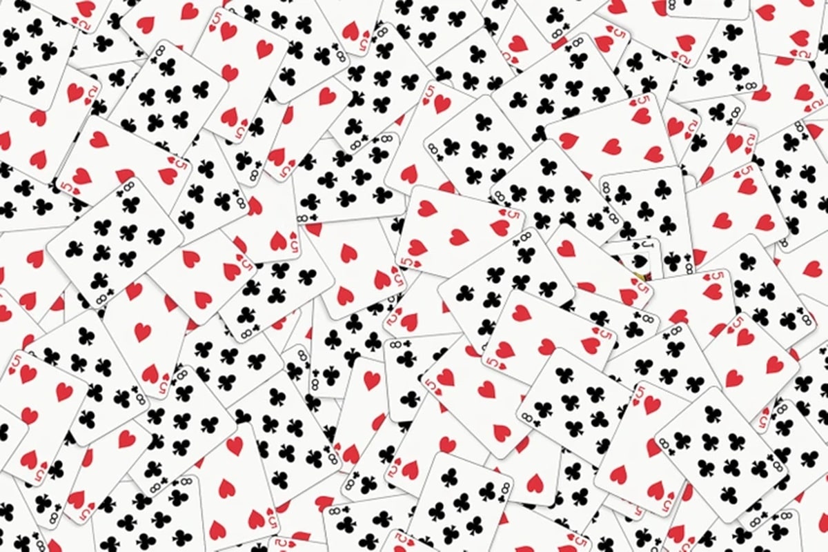 Teste de QI com uma pilha de cartas de baralho misturadas com os números 8, 5 e 2 de copas e paus.