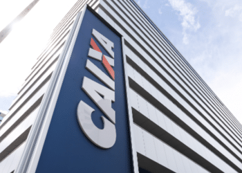 Prédio moderno da Caixa Econômica Federal visto de baixo para cima com céu ao fundo.