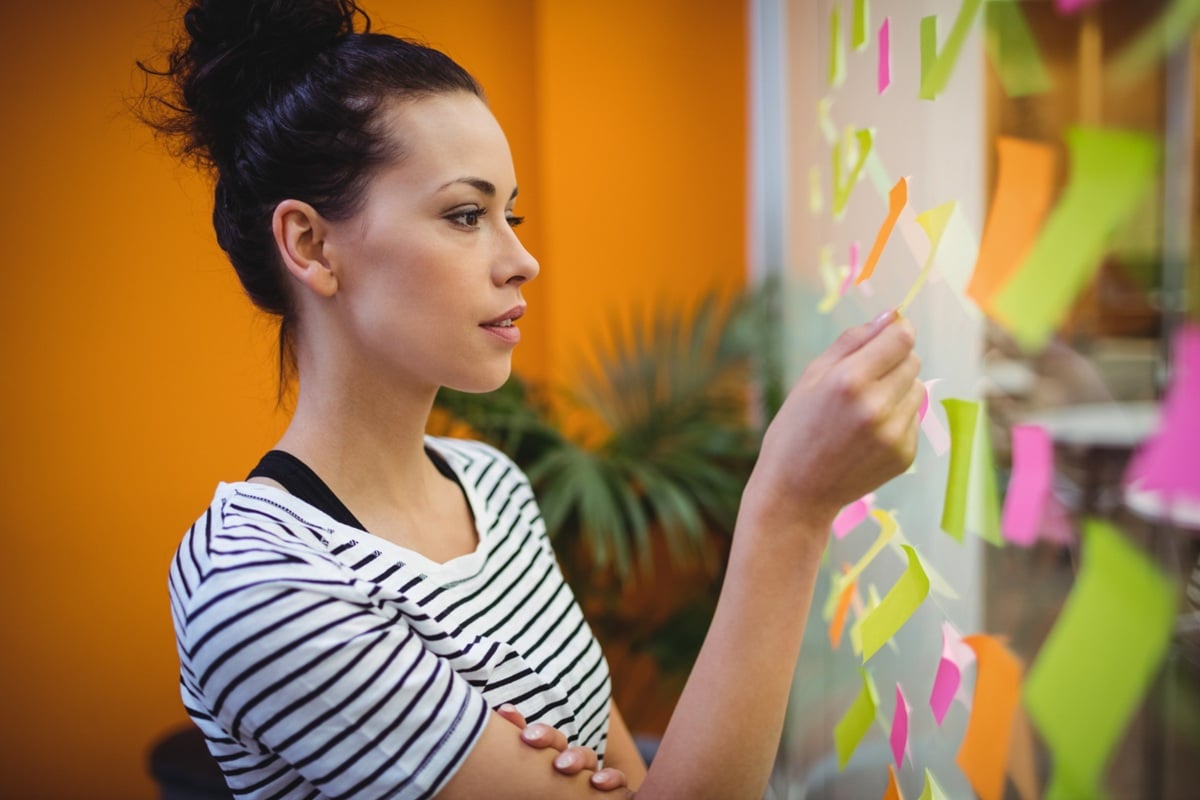 Estudante criando mapa mental com post-its coloridos em quadro branco como técnica de revisão eficiente para o Enem 2025