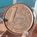 Moeda rara de 1 centavo em primeiro plano, exibindo a data de cunhagem, que pode valer até R$ 1.000 para colecionadores devido a um detalhe de erro de fabricação ou cunhagem reversa.