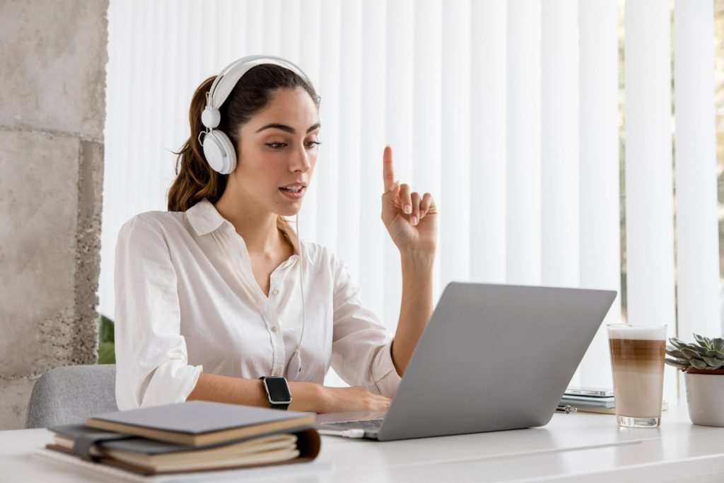 Profissional com fones de ouvido participando de uma videoconferência no computador, simbolizando a transformação digital no mercado de trabalho.