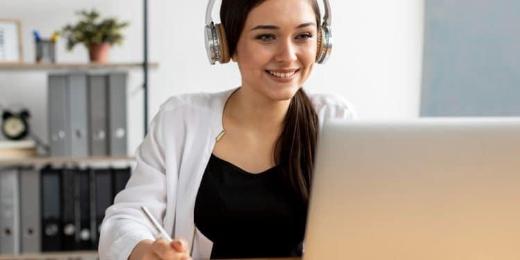 Jovem profissional participando de curso online gratuito em ambiente doméstico com computador e fones de ouvido