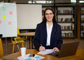 Profissional de RH estudando com materiais e laptop em ambiente corporativo