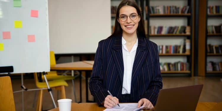 Profissional de RH estudando com materiais e laptop em ambiente corporativo
