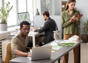 Equipe multidisciplinar trabalhando em escritório moderno com projetos sustentáveis representando profissões emergentes