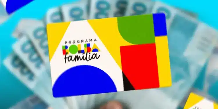Mão segurando cartão colorido do Programa Bolsa Família com várias notas de dinheiro azul em fundo desfocado