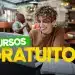 Jovem sorridente estudando com laptop em cafeteria, banner de cursos gratuitos.
