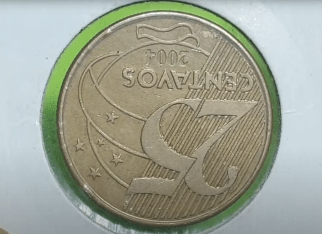 Moeda de 25 centavos de 2004 com o reverso (lado do valor) totalmente invertido, um erro de cunhagem que a torna uma peça rara e muito procurada por colecionadores.