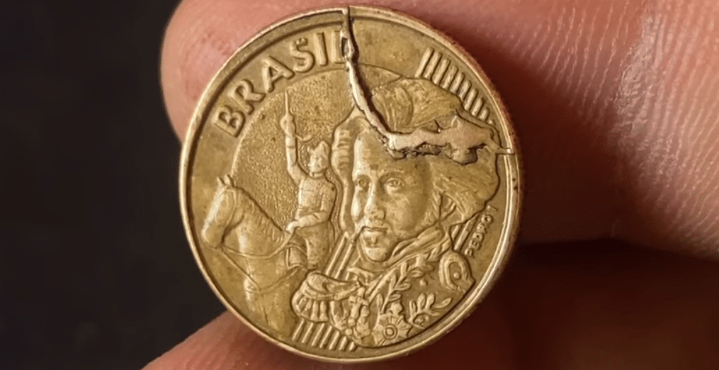 Moeda com grande falha de cunhagem (rachadura visível), representando o defeito "cunho rachado" procurado em moedas de 10 centavos de 2002.