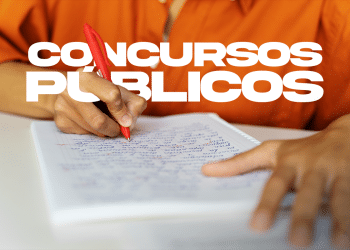 Pessoa escrevendo com caneta vermelha em caderno de anotações em preparação para concurso público.