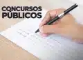 Mão masculina segurando caneta preta respondendo questões de prova de múltipla escolha para concursos públicos