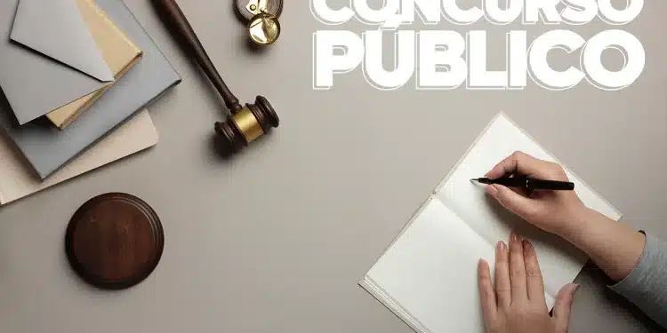 Mulher se preparando para um concurso público, com caneta na mão e um caderno, ao lado de um martelo e uma balança da justiça.