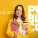 Jovem sorridente com suéter amarelo e óculos, segurando cadernos e café, preparada para concurso público