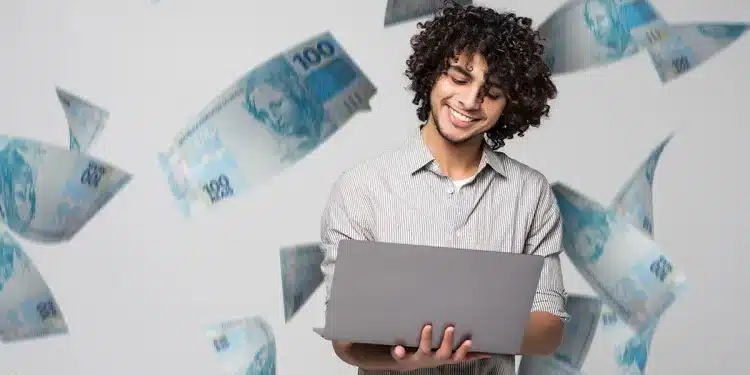 Imagem de um profissional sorrindo enquanto trabalha em seu laptop, com notas de dinheiro ao fundo, simbolizando as oportunidades no mercado de trabalho brasileiro impulsionadas por tecnologia e sustentabilidade.