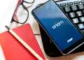 Smartphone exibindo o aplicativo do ENEM e INEP, com materiais de estudo ao lado, aguardando a divulgação dos locais de prova 2025.