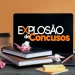 Mesa com livros, laptop mostrando Explosão de Concursos e materiais de estudo espalhados.