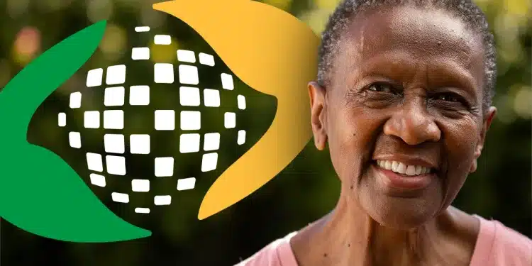 Retrato de mulher negra idosa sorrindo em ambiente externo com fundo verde desfocado